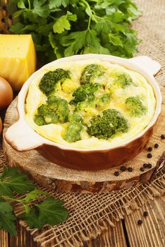 broccoli and cheese casserole in a dish on a wooden board with parsley