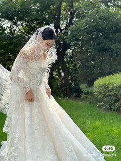 a woman in a wedding dress standing on the grass with her arms around her head