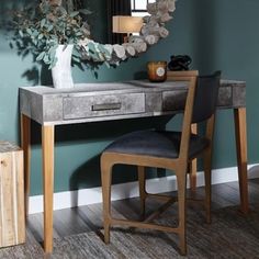 a desk with a mirror, chair and vase on it in front of a wall