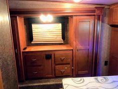 the inside of an rv with wooden cabinets and drawers, including a bed in it