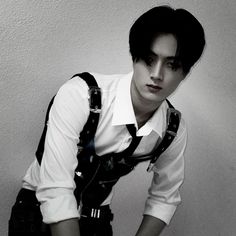 a man in suspenders and a white shirt is leaning against a wall with his hands on his hips