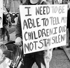 a man holding a sign that says i need to be able to tell my children z did not stay silent