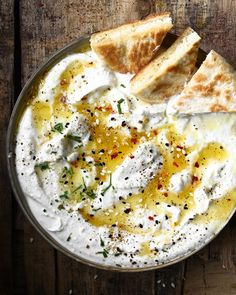 a bowl filled with hummus and pita bread on top of a wooden table