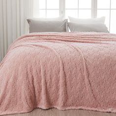 a bed covered in a pink blanket and pillows