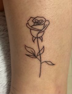 a single rose tattoo on the ankle is shown in black ink, and has a thin outline