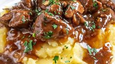 meat and gravy on top of mashed potatoes with garnishes