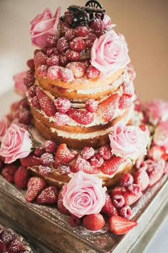 a wedding cake with strawberries and roses on top