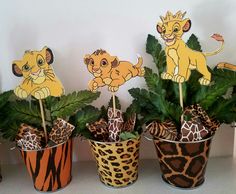 three potted plants with paper animals on them and some fake leaves in the middle