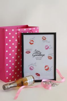 a pink gift bag with lipstick on it next to a bottle of wine