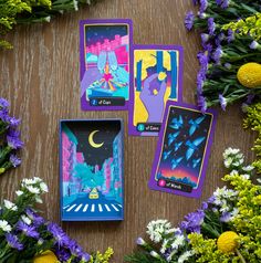 four tarot cards sitting on top of a wooden table next to purple and white flowers