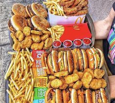 a tray full of food including burgers, french fries and other foods sitting on the ground