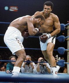 two men standing next to each other on top of a boxing ring in front of an audience