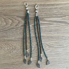 two long beaded necklaces with charms hanging from them on a wooden table top