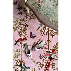 several pairs of shoes sitting on top of a pink rug with birds and flowers all over it