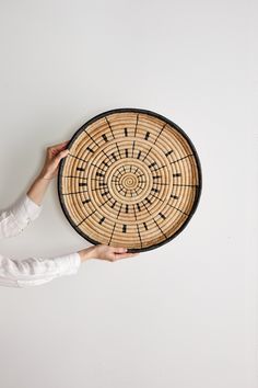 a person holding up a woven basket on the wall