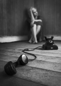 two people sitting on the floor next to an old phone and corded up telephone