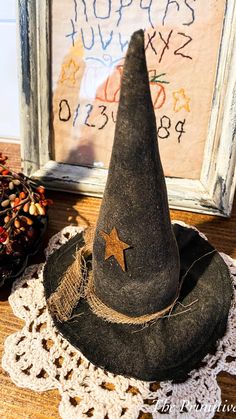 a witches hat sitting on top of a doily next to a framed sign and pine cones