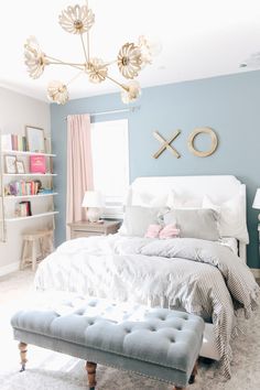 a bedroom with blue walls, white bedding and a chandelier hanging from the ceiling