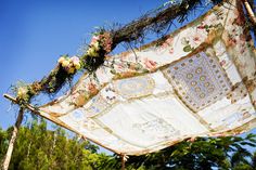 an old piece of cloth with flowers and vines on it hanging from a tree branch