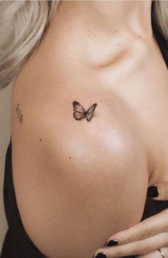 a woman with a butterfly tattoo on her shoulder and chest is looking at the camera