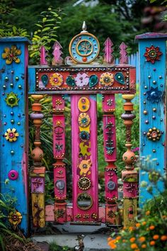 an elaborately decorated wooden gate in the middle of some plants and flowers with colorful decorations on it