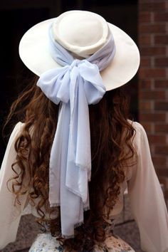 the back of a woman's head wearing a white hat with a blue bow