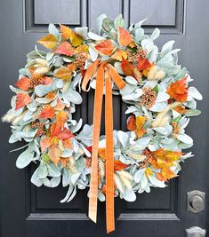 a wreath with orange and green leaves is hanging on the front door's black door