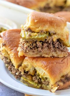 two sandwiches stacked on top of each other with meat and cheese in between them, sitting on a white plate