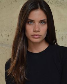 a close up of a person wearing a black shirt with long hair and blue eyes