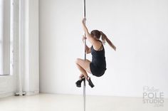 a woman is hanging upside down on a pole