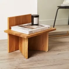 a small wooden table with a book on it and a coffee cup sitting on top