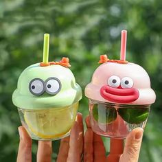 two ice cream cones with googly eyes and faces on them are being held up by someone's hand