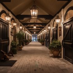 a long hallway with lights and potted plants on either side of the doorways