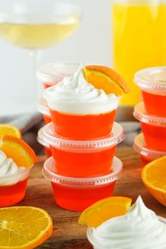 orange jello cups with whipped cream and an orange slice on the top, surrounded by sliced oranges