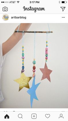 someone is holding up a mobile with three stars hanging from it's sides and beads on the strings