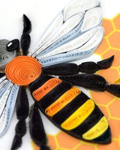 an insect made out of paper on top of a yellow and orange table cloth with scissors