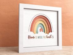 a white frame with a rainbow and the words home is where the heart is