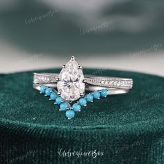 an engagement ring with turquoise beads and diamonds in it on top of a green velvet box