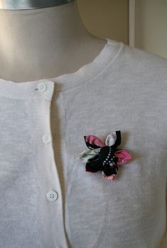 a white sweater with a black and pink flower on it