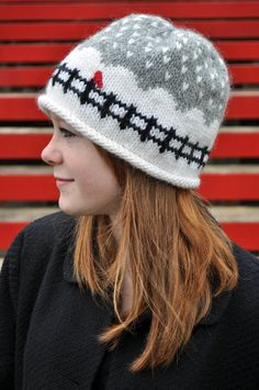 a woman wearing a knitted hat sitting in front of a red bleachers