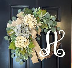 a monogrammed wreath with flowers and greenery on the front door