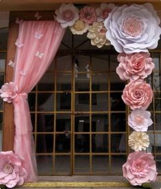 an image of a window decorated with paper flowers and pink draping on the windowsill