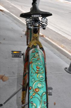 the front end of a colorful bicycle parked next to a sidewalk