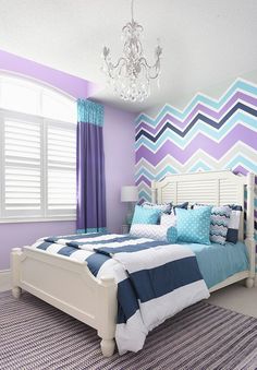 a bedroom decorated in purple, blue and white with a chandelier hanging from the ceiling