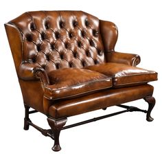 a brown leather couch sitting on top of a wooden frame with an armrest and foot rest