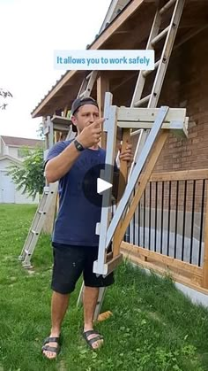 a man standing in front of a house holding a ladder up to the side of it