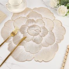 a white table topped with gold colored utensils next to a cup and saucer