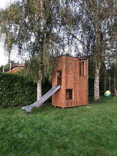 a wooden structure with a slide in the grass