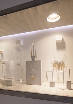 an assortment of jewelry displayed on display in a store window with white walls and flooring