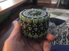 a hand holding a beaded object on top of a table